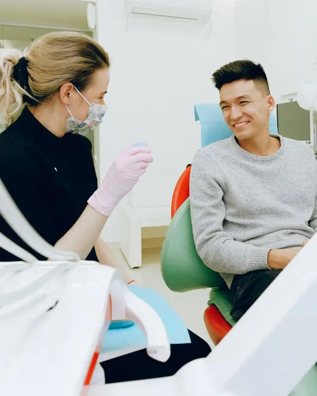 Dentist chatting with a smiling patient at the clinic